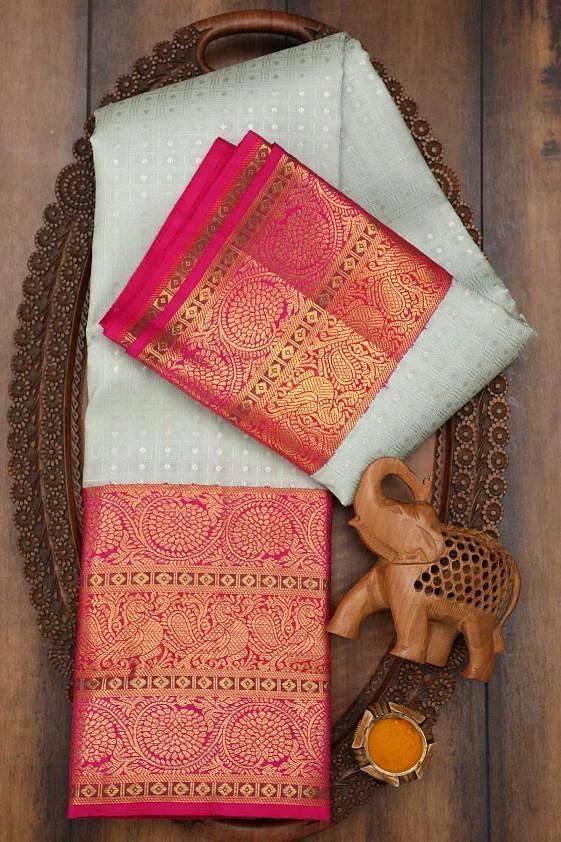 Traditional pink and gold saree with elephant design on a wooden tray