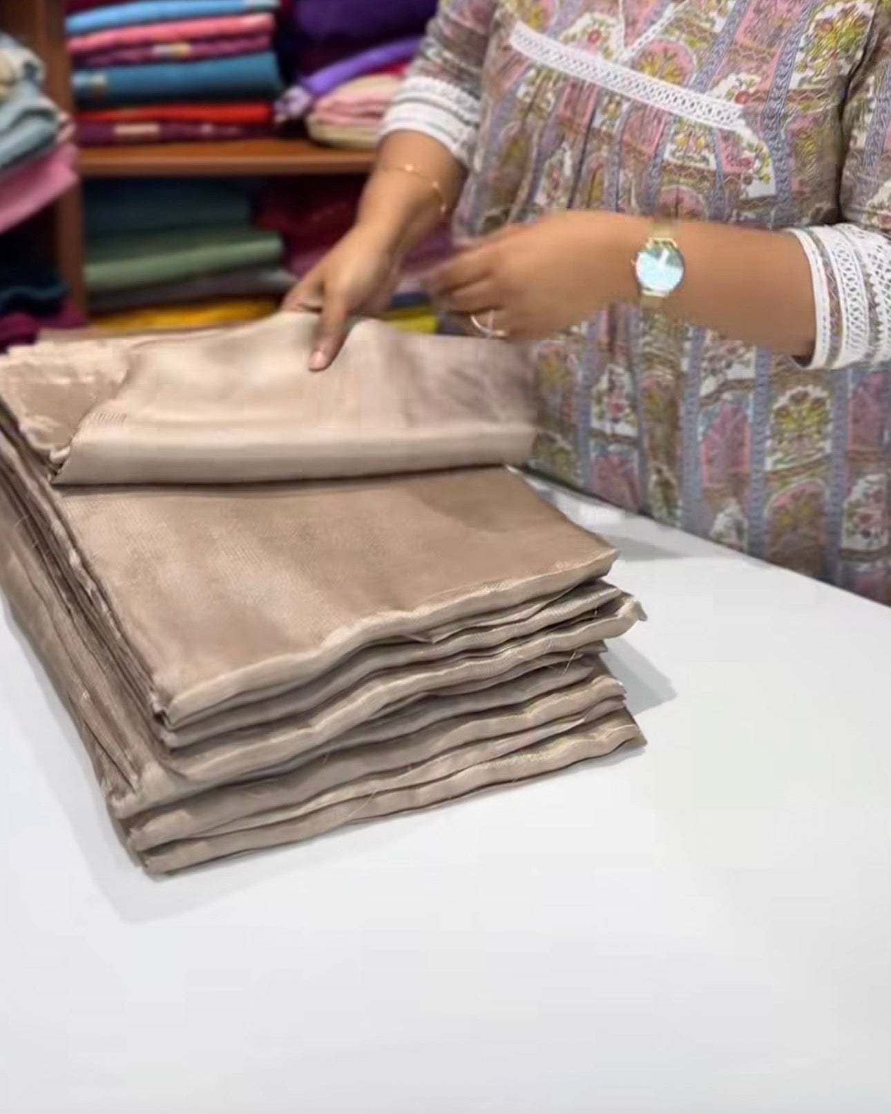 Woman arranging folded fabric in a textile store