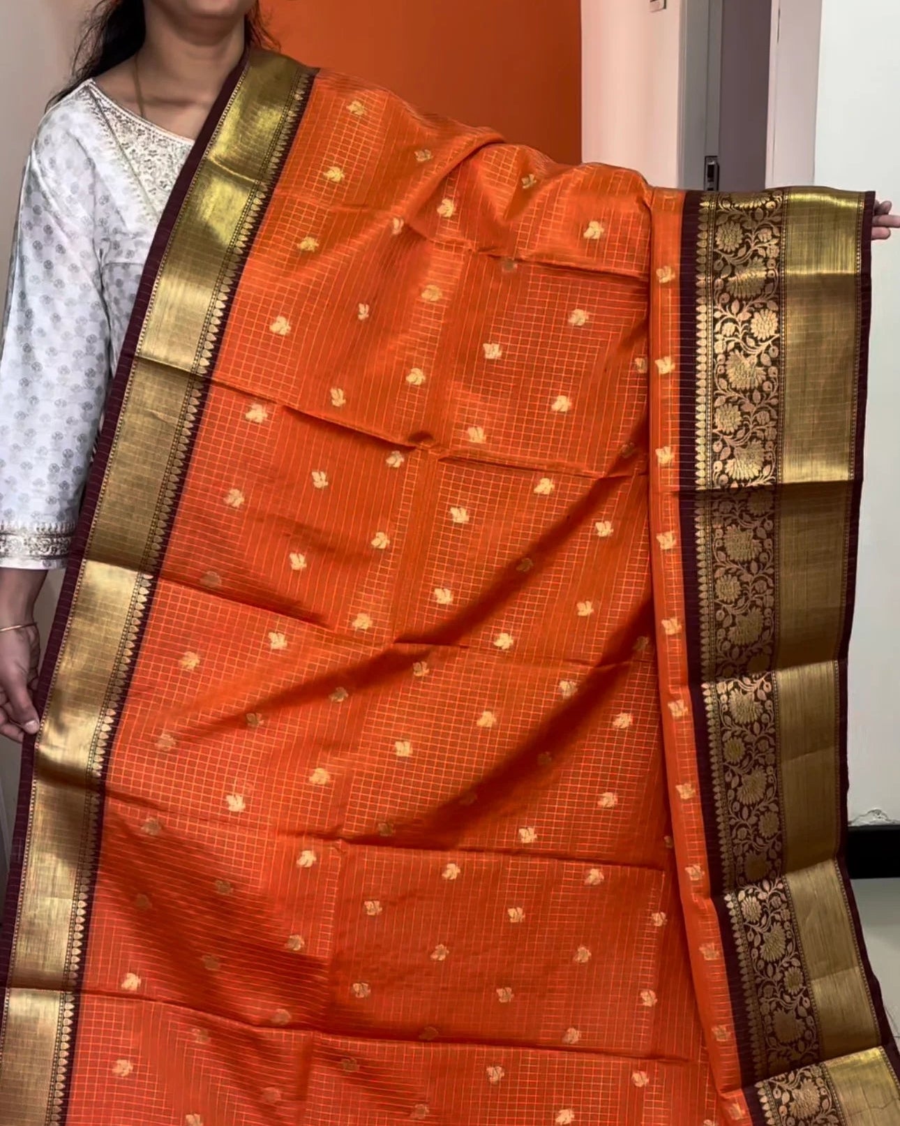 Orange saree with gold border held by a person
