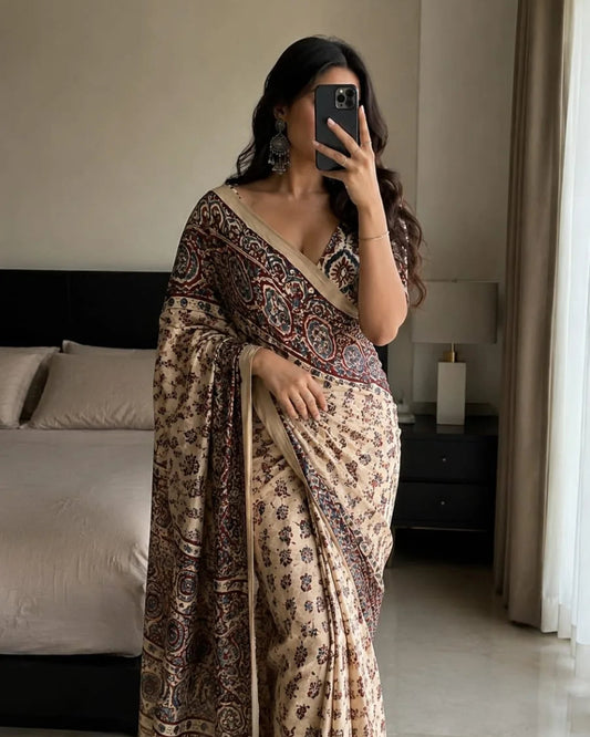 Woman taking a mirror selfie wearing a patterned saree in a bedroom.