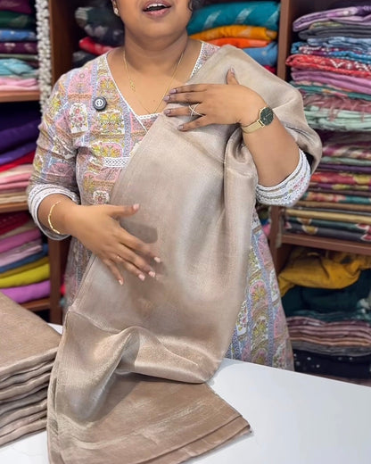 Woman holding a beige fabric in a fabric store with colorful fabrics in the background.
