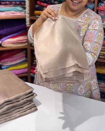 Woman holding beige fabric in a fabric store with stacks of fabric in the background