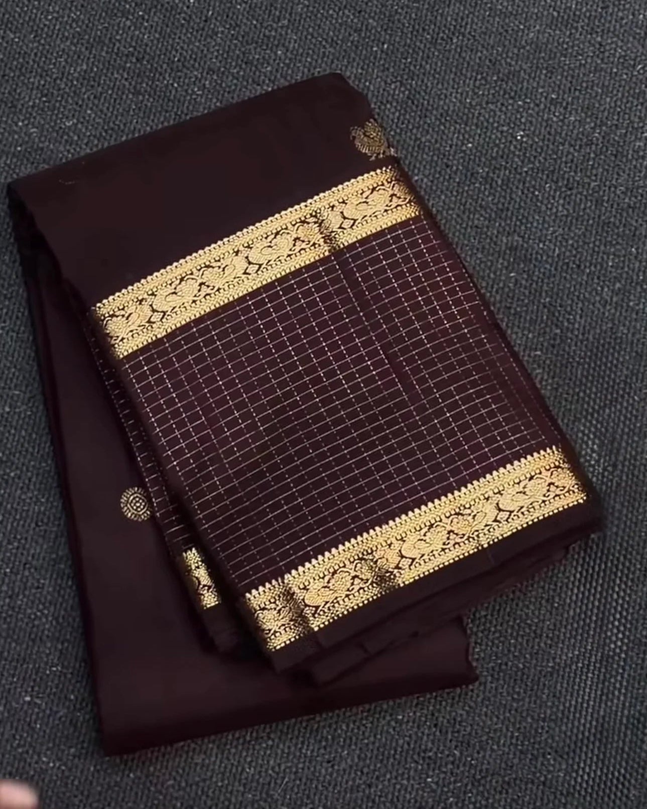 Brown fabric with gold lace trim on a textured surface