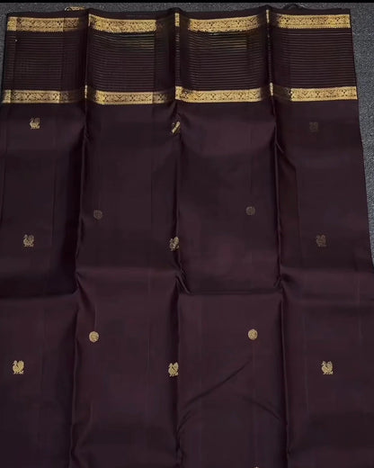 Dark purple fabric with gold patterns and a hand holding it on a dark background