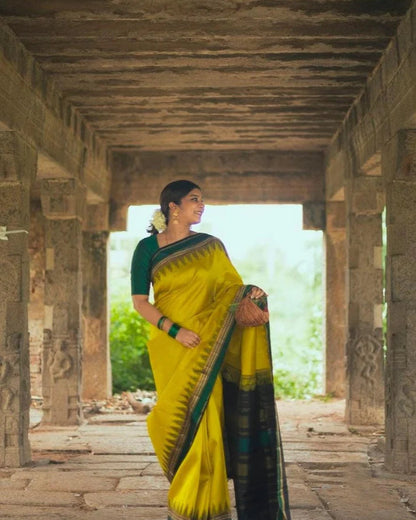 Woman in a yellow saree standing in an ancient temple setting
