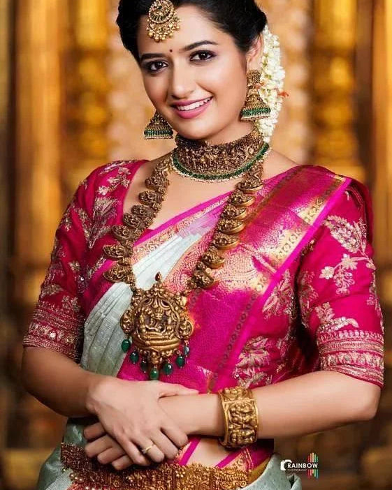 Woman in traditional pink saree with gold jewelry against a warm-toned background