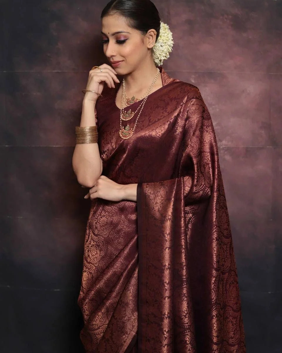 Woman wearing a maroon saree with a textured pattern against a dark background