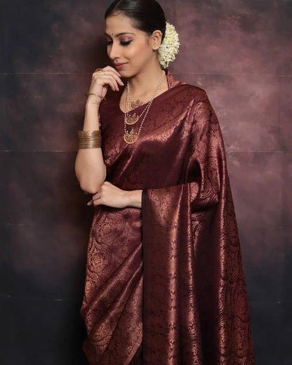 Woman wearing a maroon saree with a textured pattern against a dark background