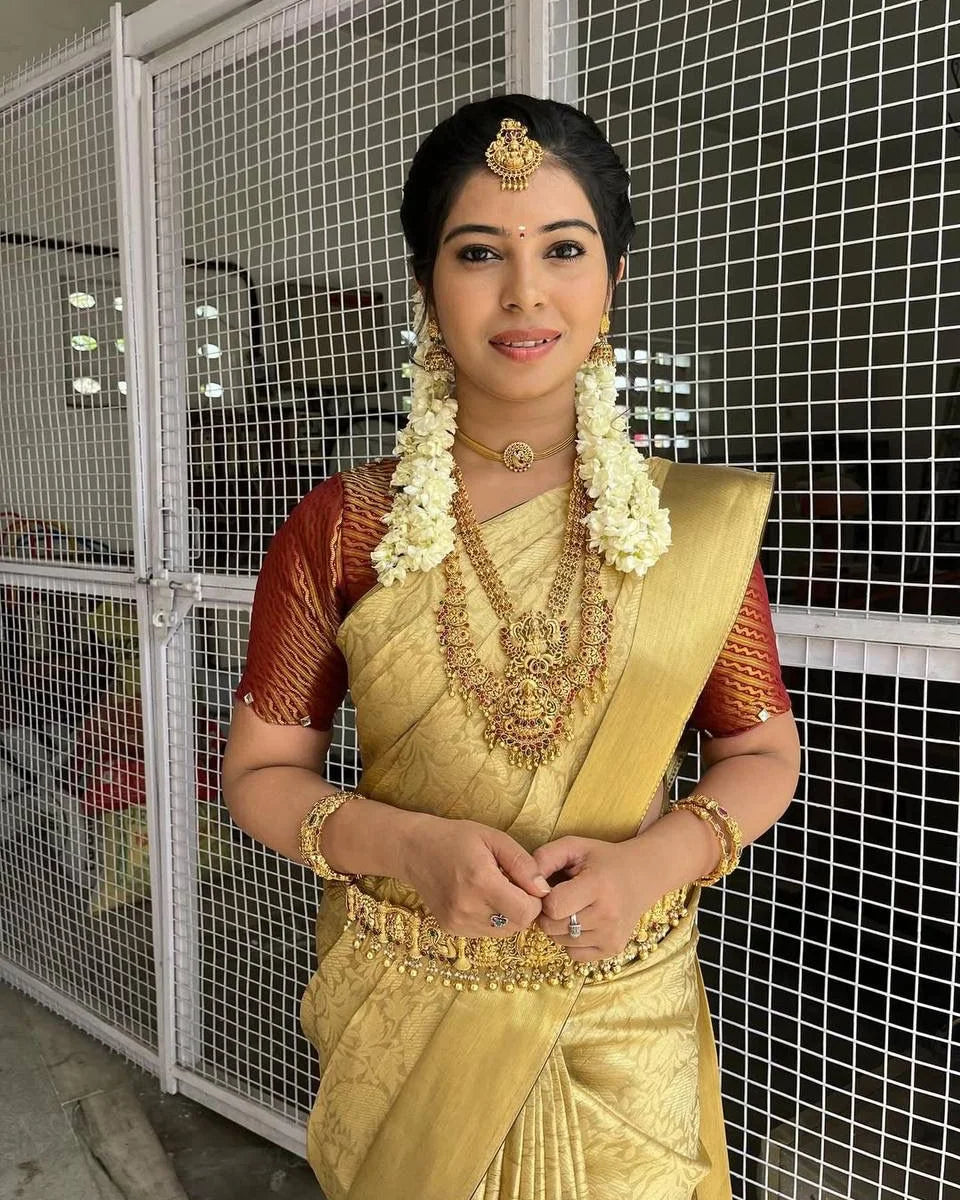 Woman in traditional gold saree with jewelry against a wire mesh background