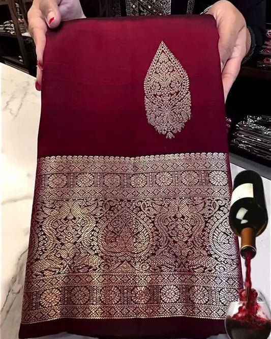 Red fabric with silver embroidery held by a person, with a bottle of wine in the background.
