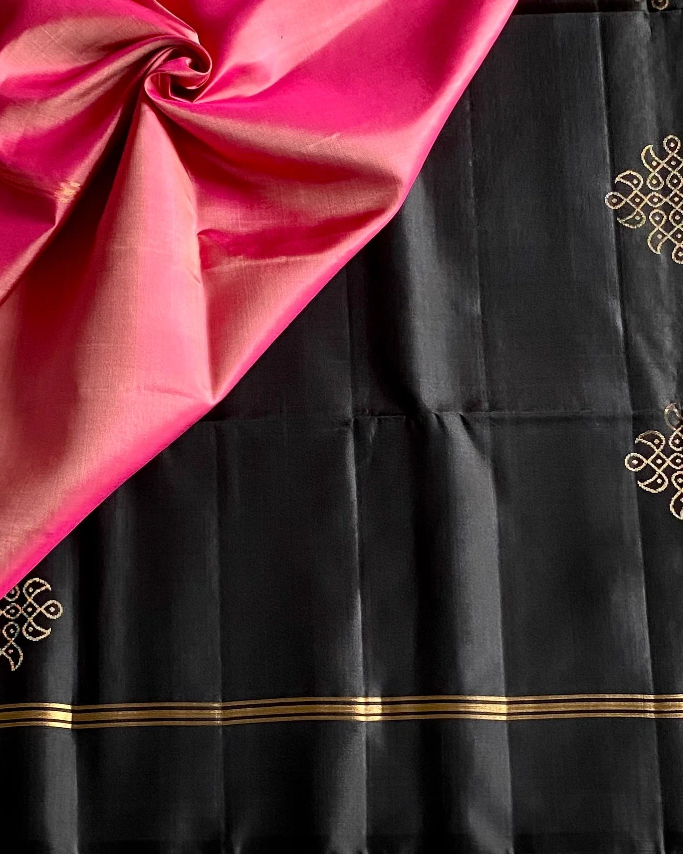 Black fabric with gold patterns and pink fabric in the corner