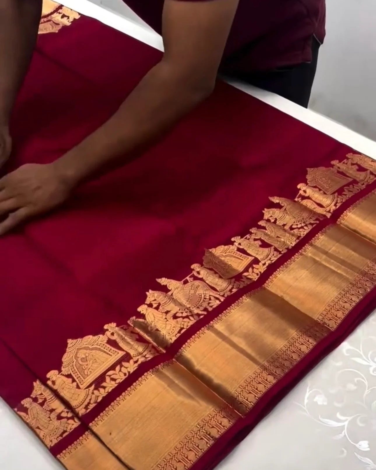 Red saree with gold border on a white table