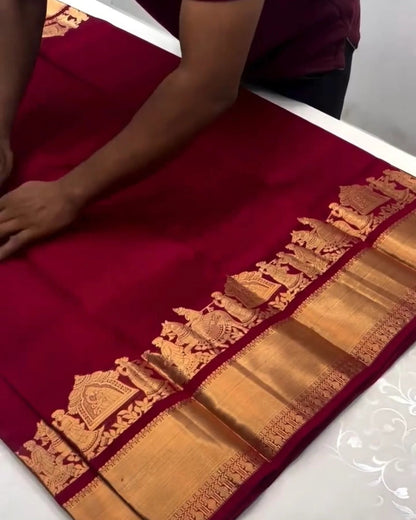 Red saree with gold border on a white table