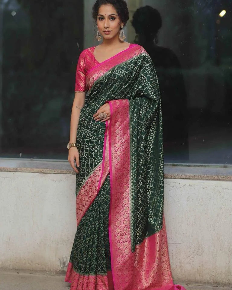 Woman wearing a green and pink saree against a reflective glass wall.