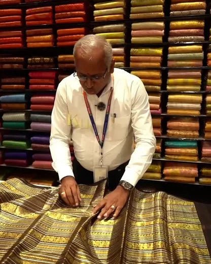 Man examining fabric in a store with colorful fabric rolls in the background