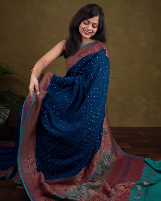 Woman wearing a blue saree with a patterned border against a brown background
